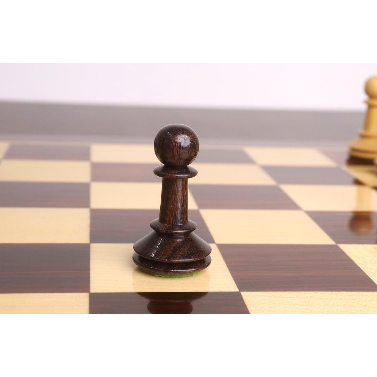 A single dark rosewood pawn from the 3.5" Monolith miniature chess set placed on a board.
