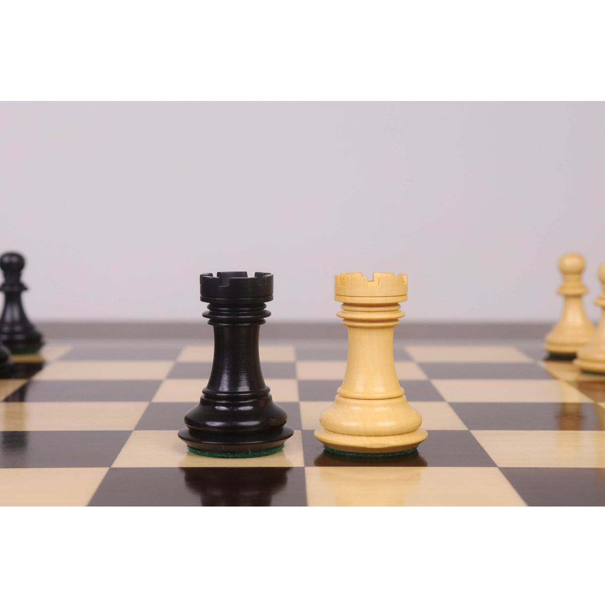 Black ebony and white boxwood luxury chess rooks facing each other on a chessboard.