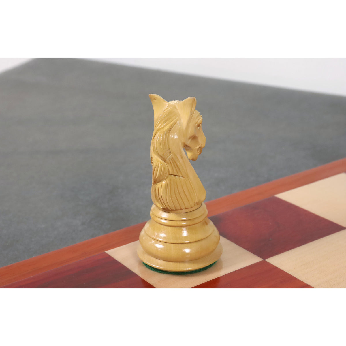 Profile view of a hand-carved natural boxwood knight piece from a luxury chess set.