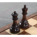 High-angle shot of the mahogany stained King and Queen pieces on a chessboard, showing the elegant 1950s vintage profile.
