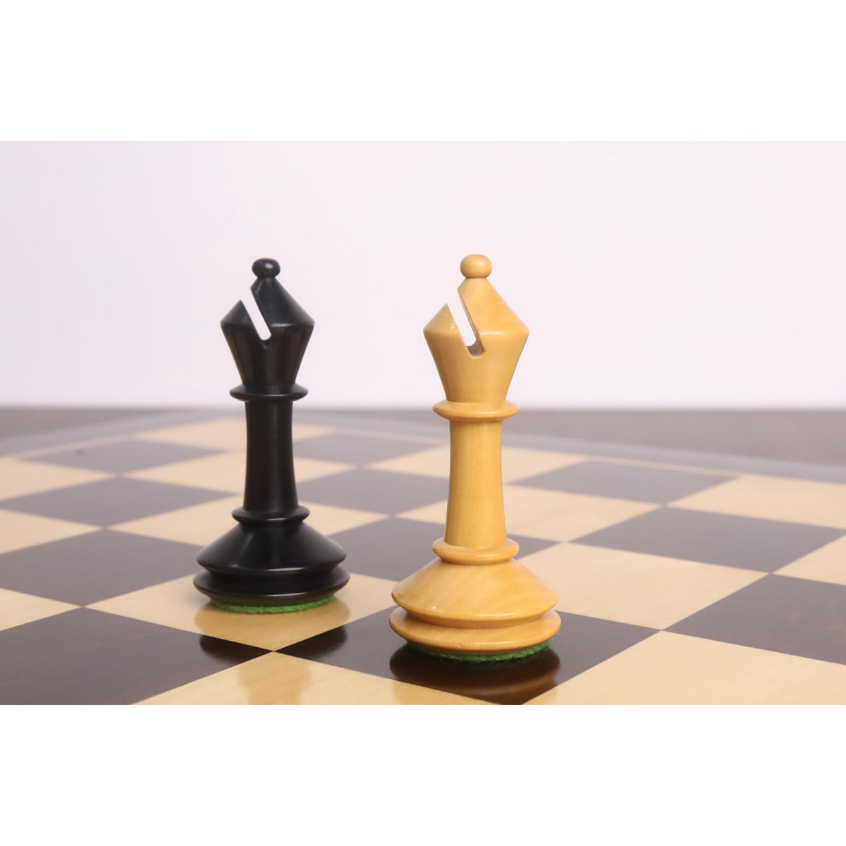 Ebonised and boxwood bishops from the 3.5-inch Monolith miniature chess set standing side-by-side on a board.