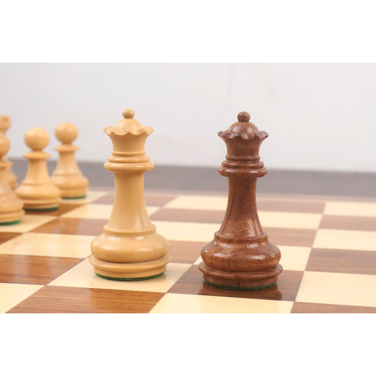 Weighted Staunton queens in boxwood and golden rosewood with traditional crenellated crowns.