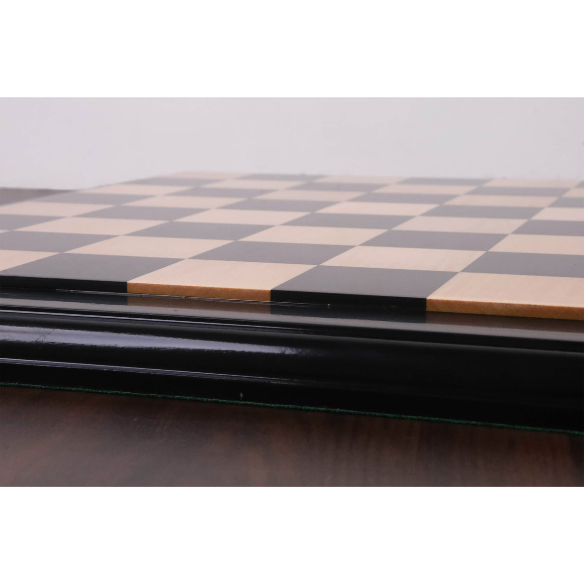 Low-angle shot focusing on the height of the raised tiles on the luxury Ebony and Maple wood chessboard.