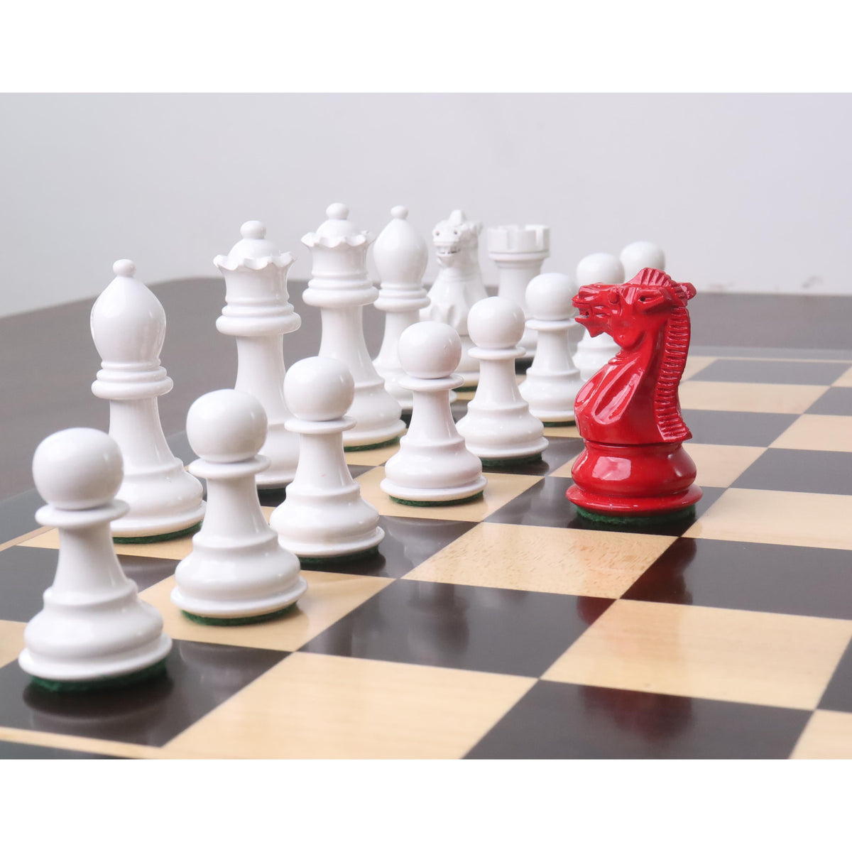 Bold red Pro Staunton knight positioned against a line of white wooden chess pieces.