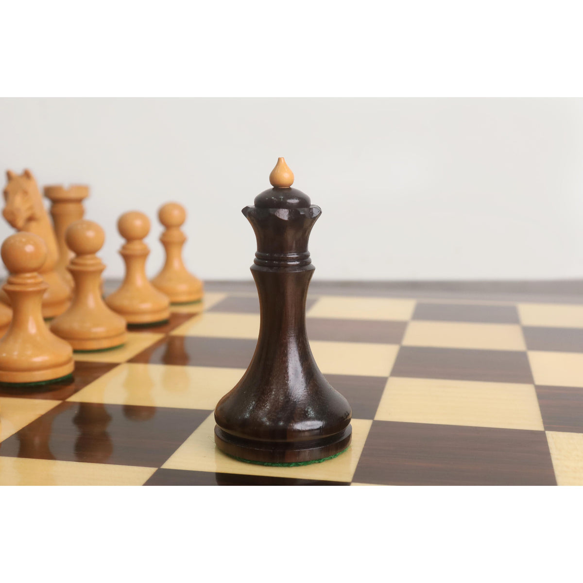 Detailed view of the dark rosewood queen from the 3.8" Candidates Series minimalist chess set on a wooden board.