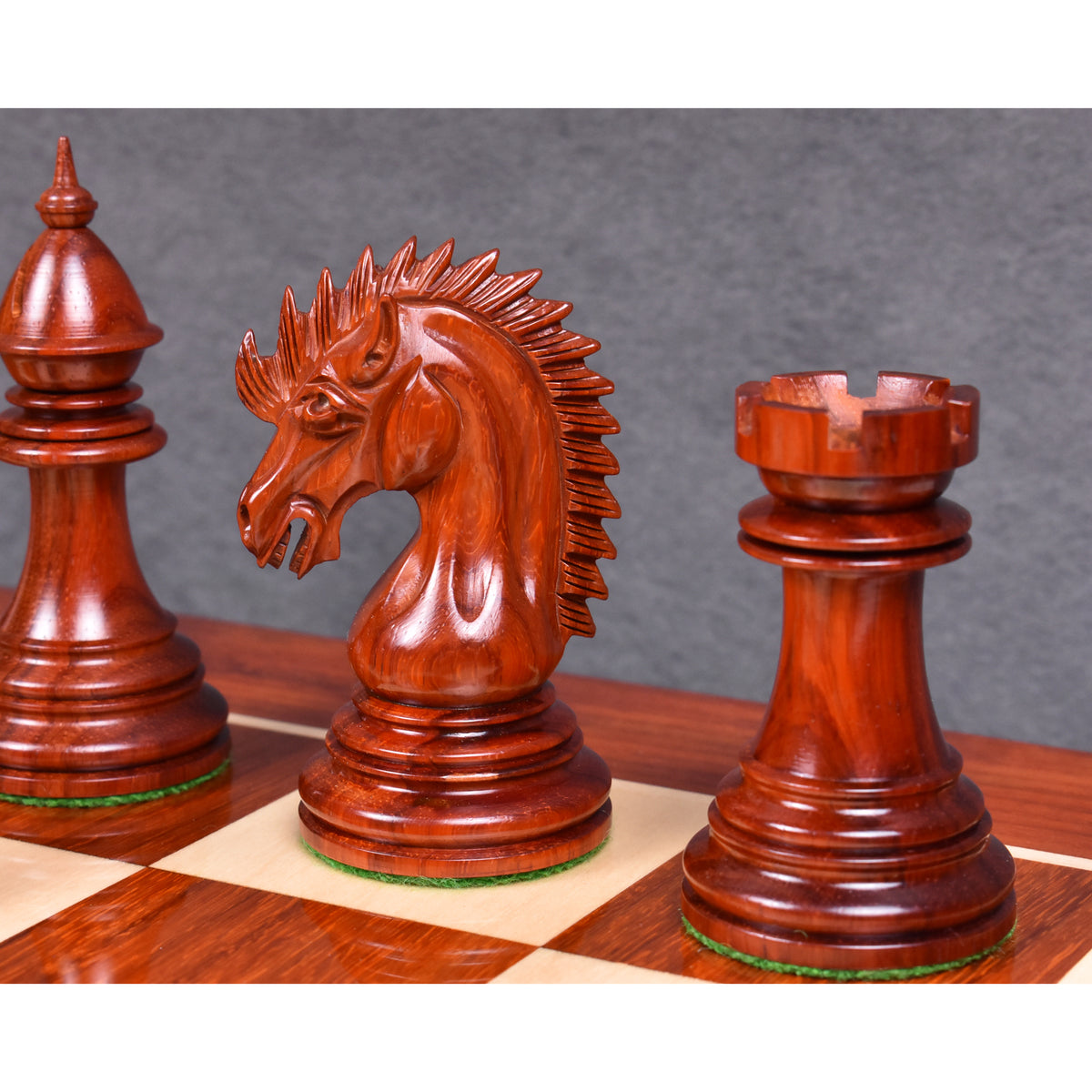 A detailed shot of the dark Bud Rosewood Dragon Knight and Rook on a wooden chessboard.