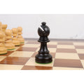 Close-up of the black ebonised boxwood Bishop from the Taj Mahal chess set resting on a board.