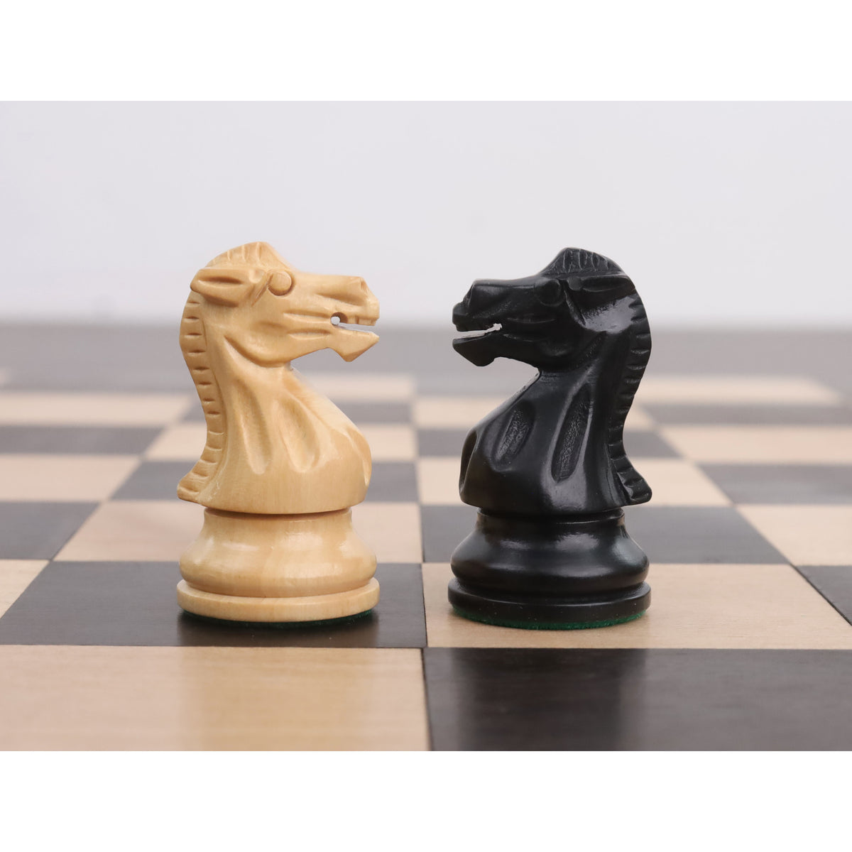 Hand-carved knights in ebonised and boxwood finishes standing on a checkered board.