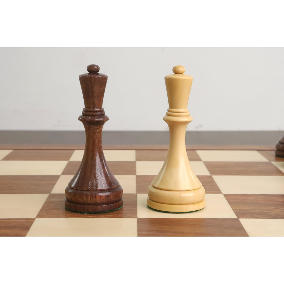 Golden rosewood and boxwood chess queens side by side on a board