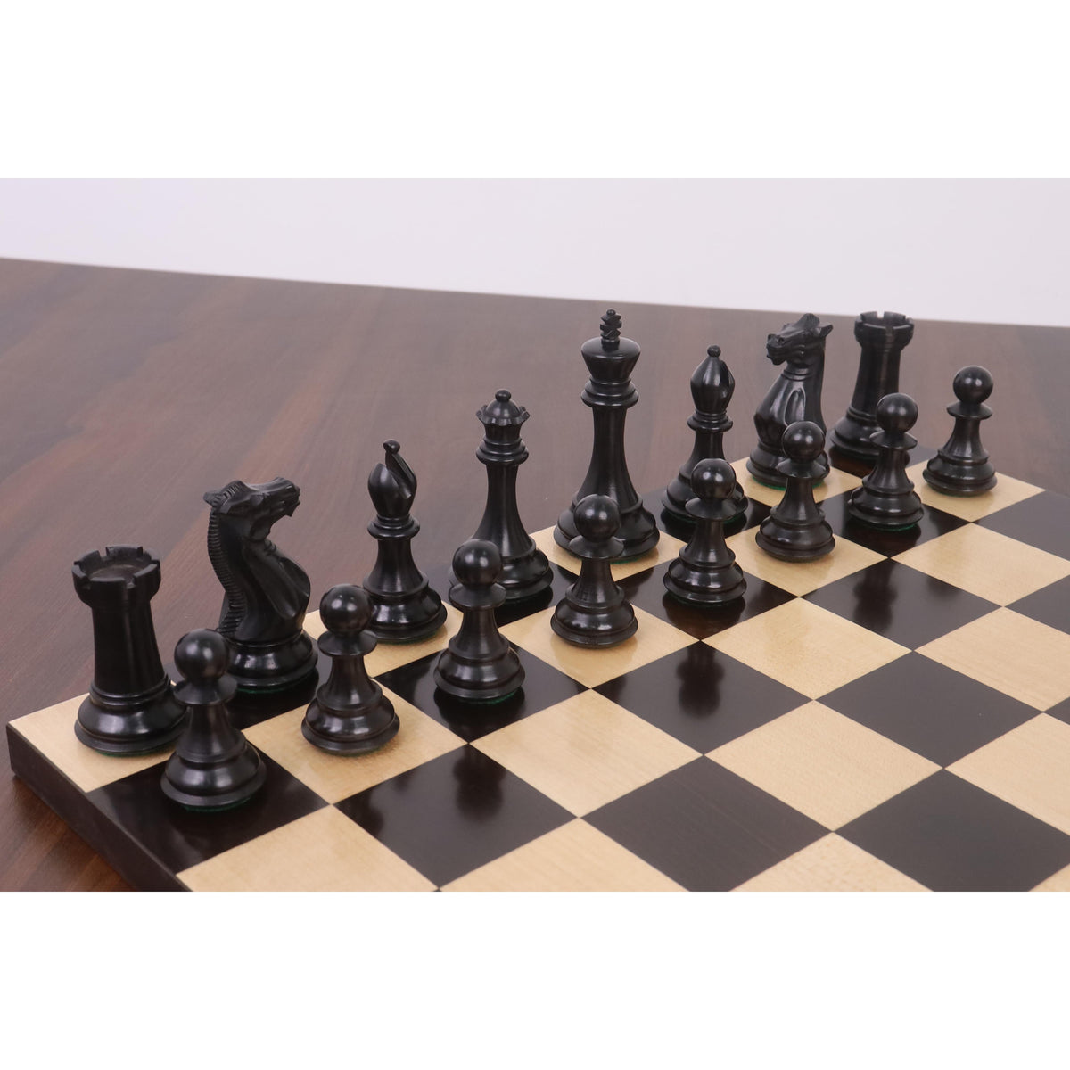 Diagonal arrangement of the black Sleek Staunton ebony chess pieces on a board.