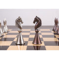 Close-up of metallic silver and antiqued copper Knight chess pieces.