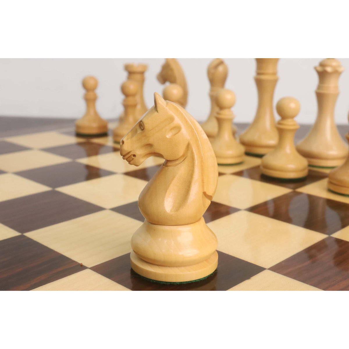 Profile view of the natural boxwood Knight from the 3.8" Candidates Series Minimalist chess set on a board.