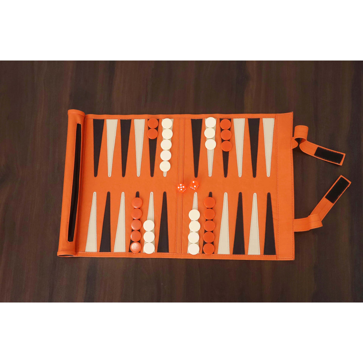 Professional-grade orange roll-up backgammon board set up on a wooden table.