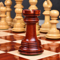 Hand-crafted bud rosewood rook chess piece centered on a polished wooden chessboard square.