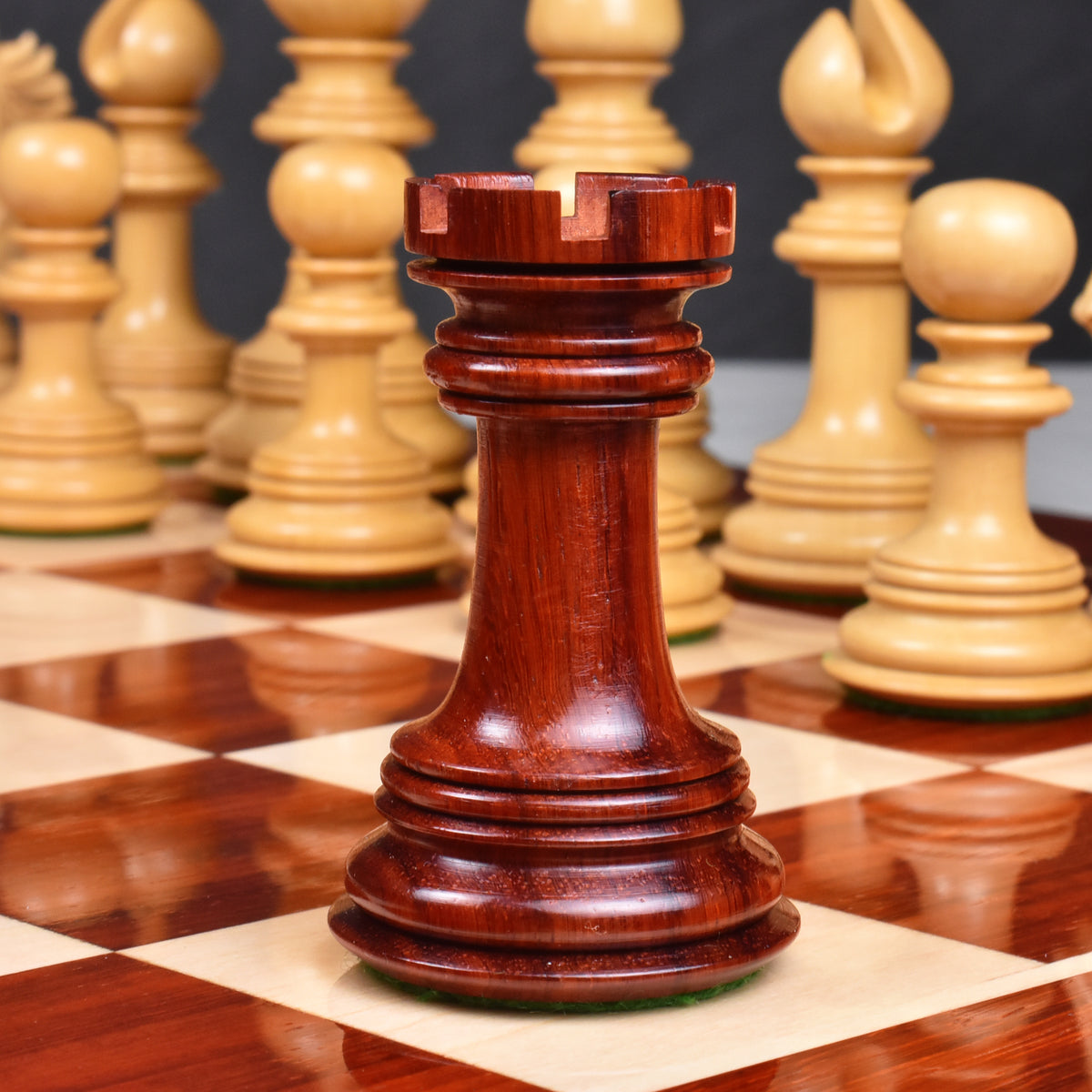 Hand-crafted bud rosewood rook chess piece centered on a polished wooden chessboard square.
