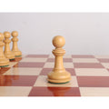 Single light-colored pawn from the 4.6" Bath Luxury Staunton chess set on a wooden board.
