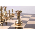 Close-up of a gold rook from the Splendor Series brass luxury chess set on a board, with other pieces blurred behind.