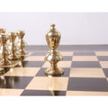 Gold brass Victorian metal chess bishop standing on a glossy chessboard.