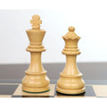 Premium white boxwood Staunton king and queen chess pieces standing on a polished inlaid wood chess board.