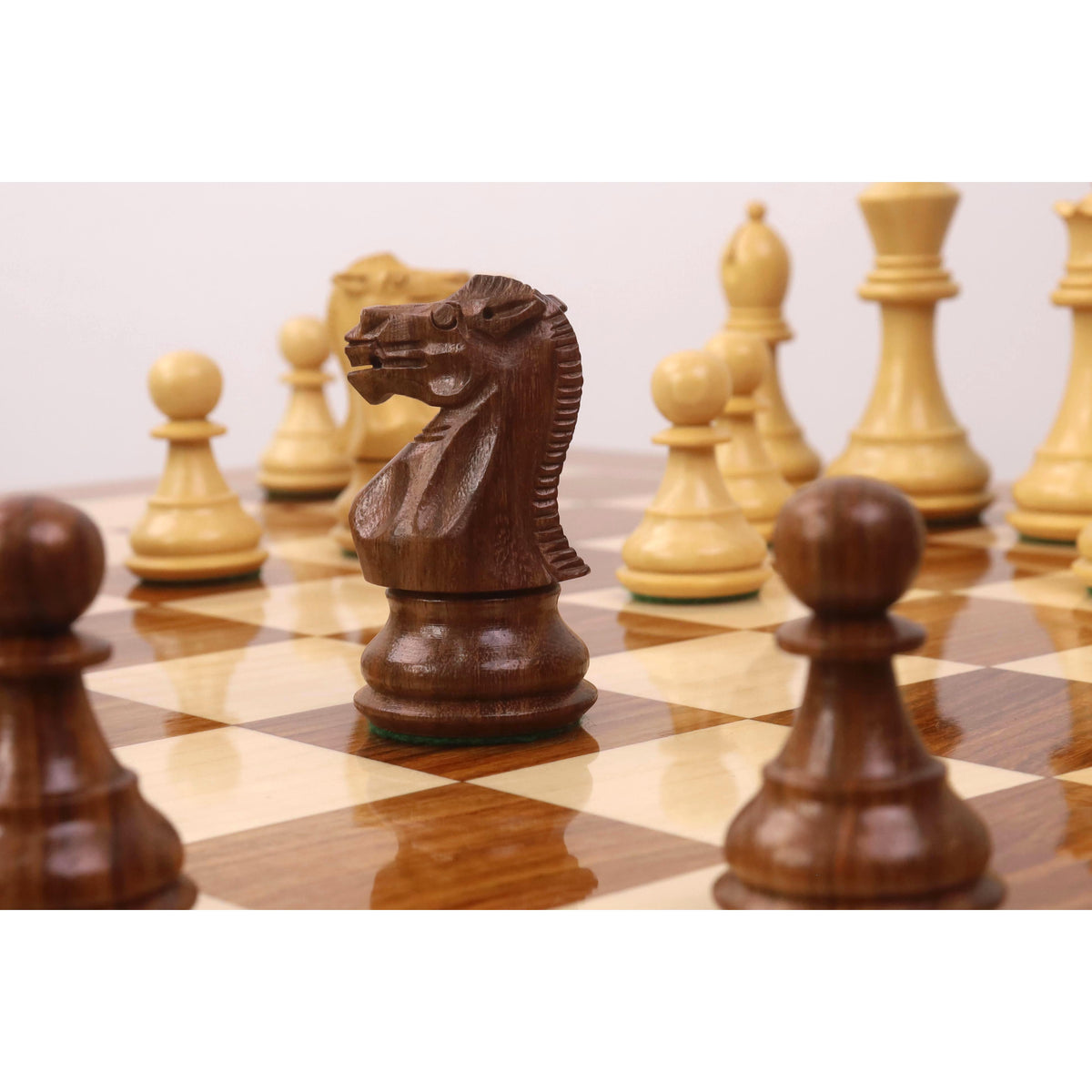 Close-up of a golden rosewood knight piece on a Monarch series wooden chess table.