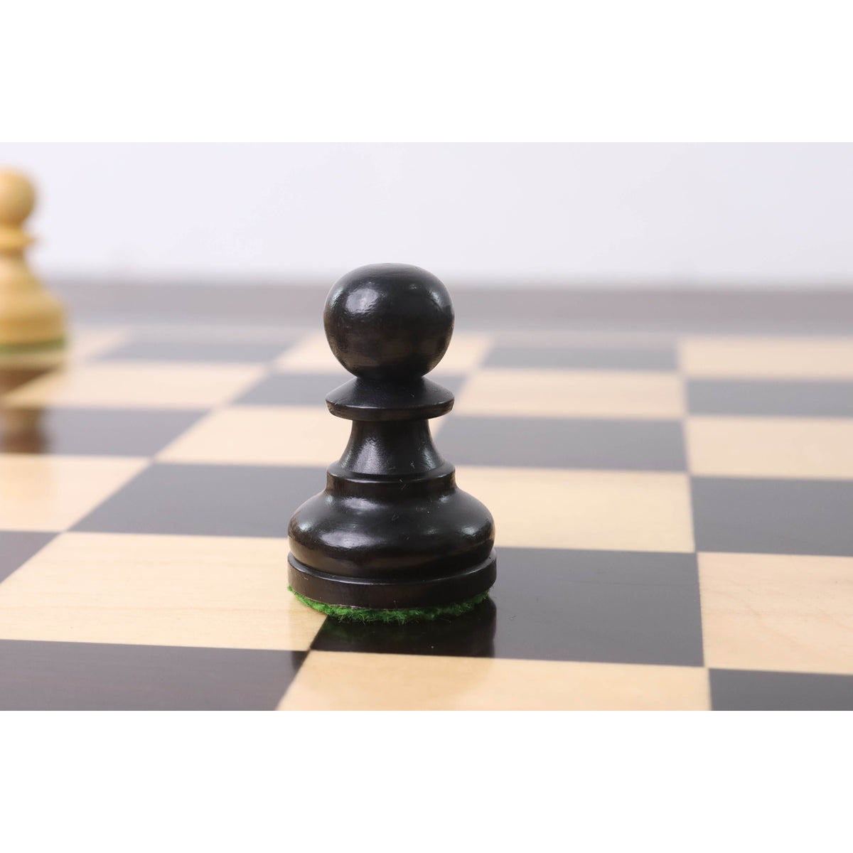 Close-up of a single Ebonised Staunton pawn on the chessboard.