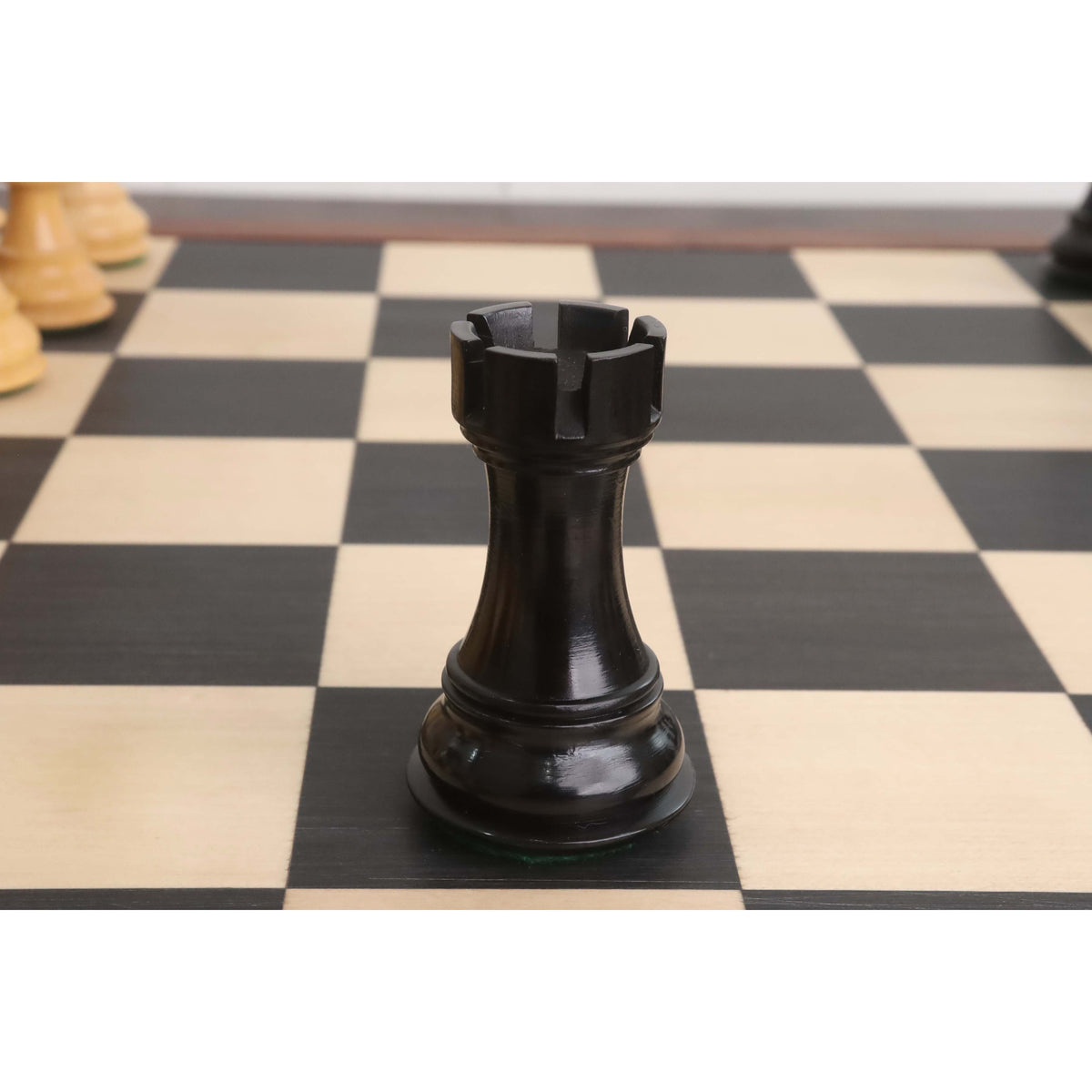 Ebonised boxwood rook from the 4" Fierce Knight Staunton chess set displayed on a chessboard.