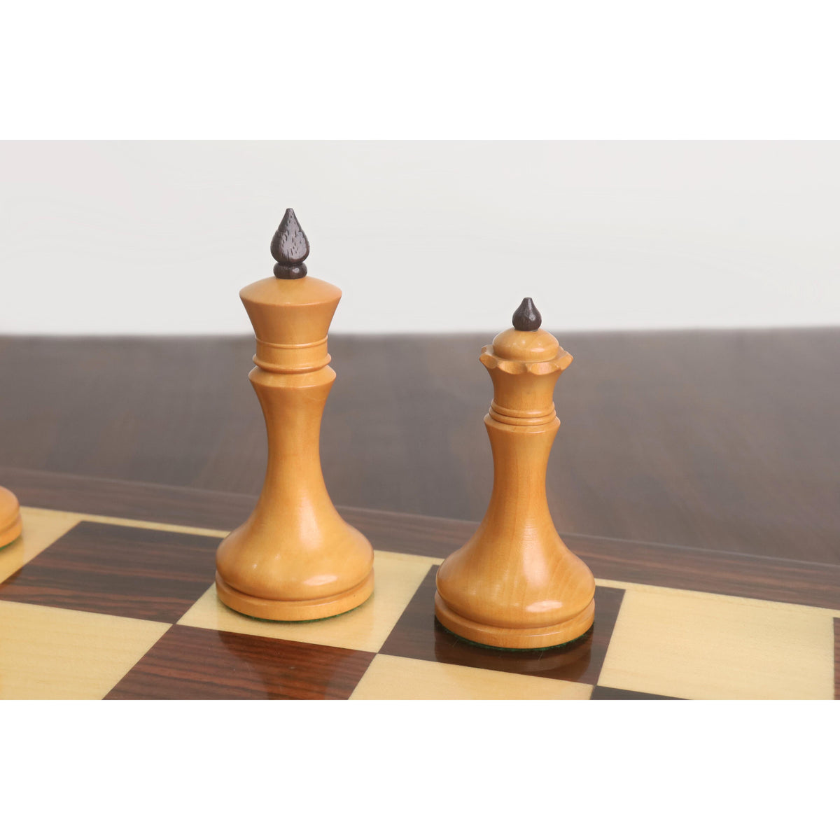 Antiqued boxwood king and queen from the 3.8" Candidates Series minimalist chess set displayed on a chessboard.