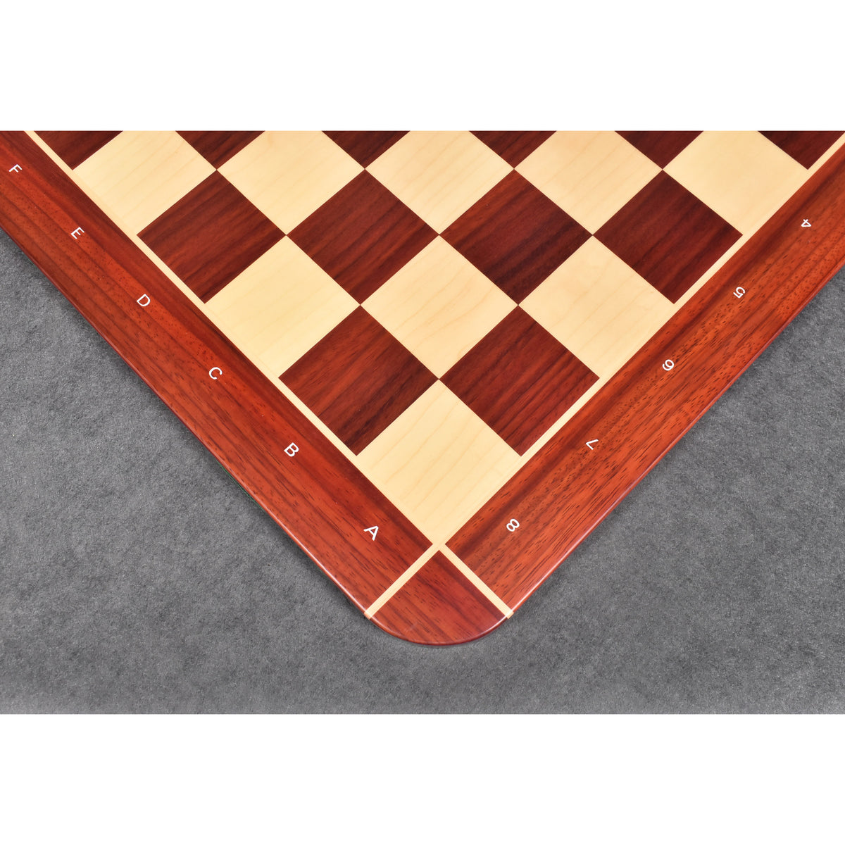 High-angle corner shot of the algebraic notations on a red Bud Rosewood border against a dark grey background.
