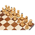 High-angle view of the natural boxwood chess pieces arrayed on a wooden chessboard's starting ranks.