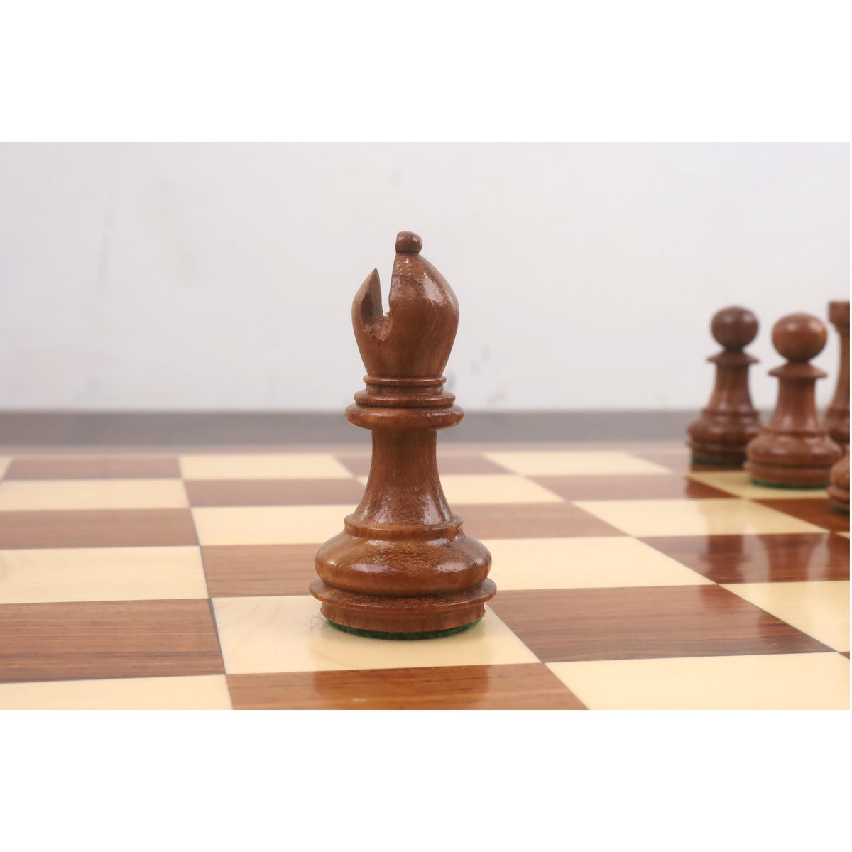 Hand-polished golden rosewood Staunton bishop piece with a deep miter cut and felted base.