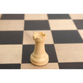 Single boxwood rook showcasing the turrets and grain on a black and tan chess board.