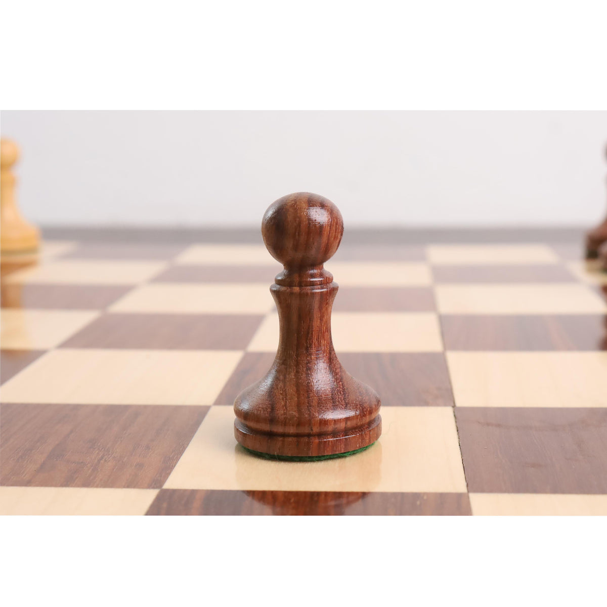 Minimalist golden rosewood pawn centered on a premium wooden chess board.