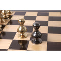 Gold and grey Victorian metal pawns positioned together on a chessboard.