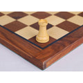 Detailed view of a classic boxwood rook chess piece resting on a maple and walnut board.