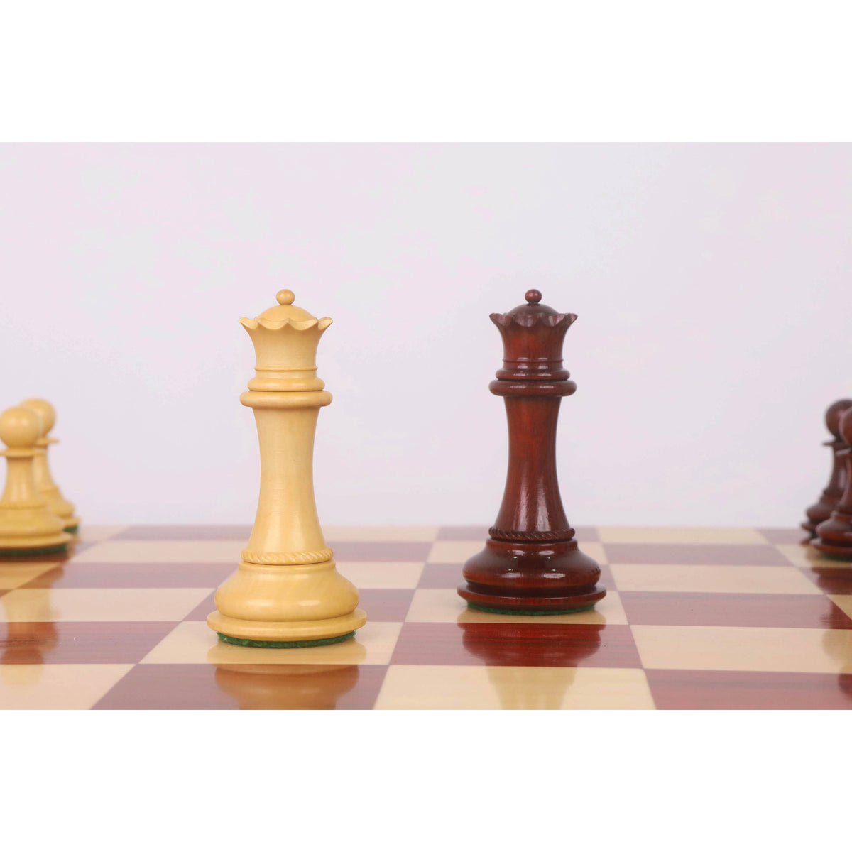 Boxwood and bud rosewood Queens from the 4.5 inch Incitatus luxury Staunton chess set standing on a glossy board.