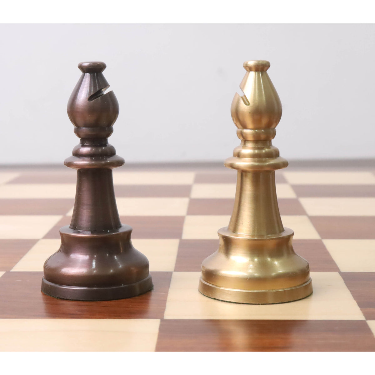 Side-by-side antiqued copper and matte gold bishops from the Pro Staunton brass metal luxury chess set.