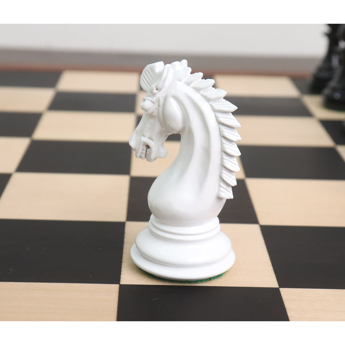 Close-up profile of a white texture painted Staunton Knight chess piece facing left on a wooden chessboard.