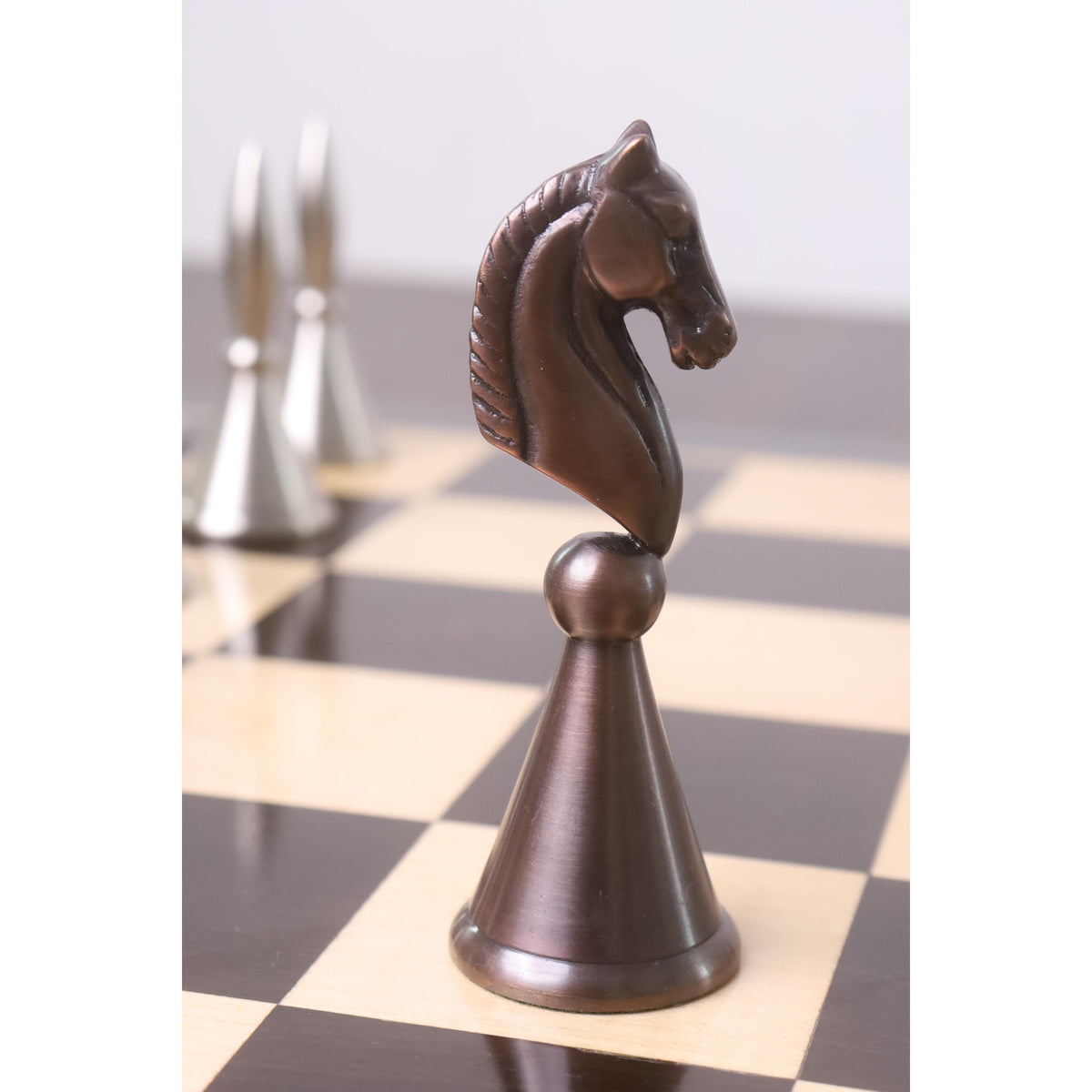Close-up of an antiqued copper Knight chess piece on a wooden board.