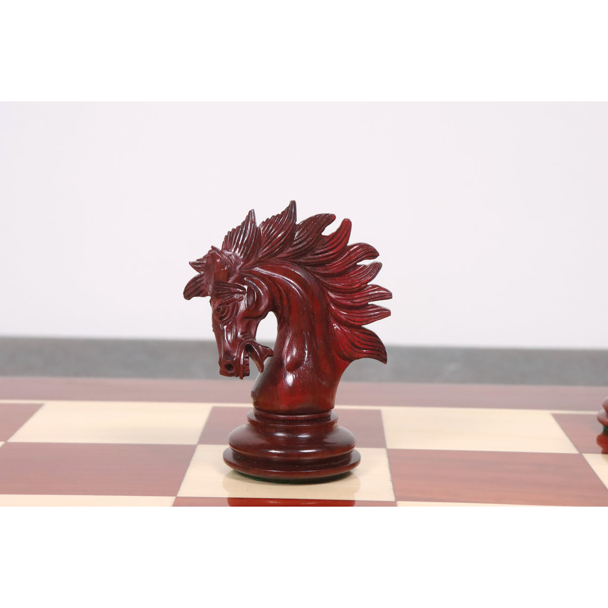 Detailed profile of a handcrafted crimson stained Knight chess piece on a glossy chessboard.