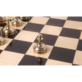 Single gold pawn from the 3.7" Splendor Series brass metal luxury chess set positioned on a glossy wooden chessboard.