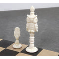Beautifully carved white camel bone owl pawn and matching tall owl piece displayed on a wooden chessboard.