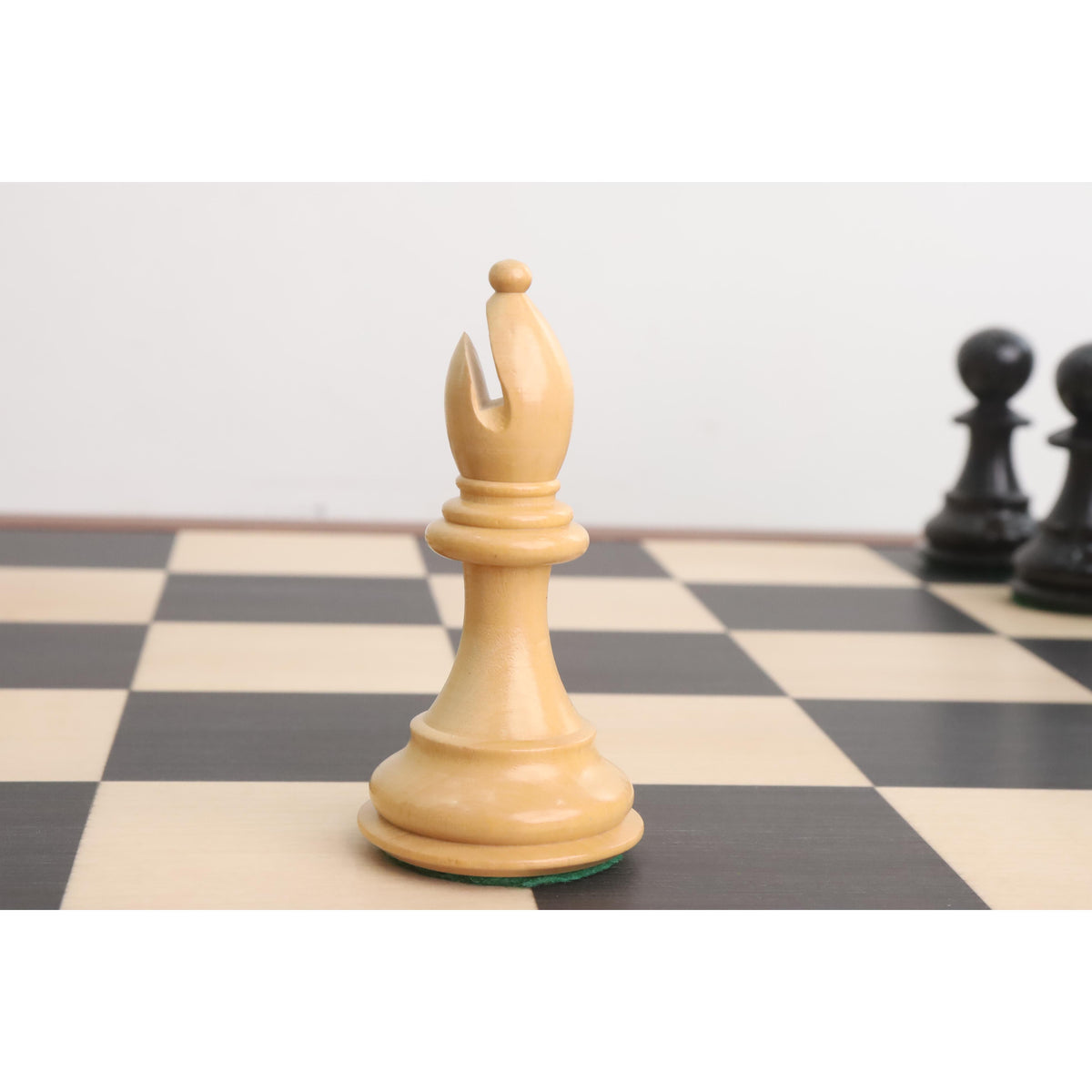 Natural boxwood bishop from the 4" Fierce Knight Staunton chess set resting on a chessboard.