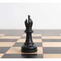 Single ebonised boxwood bishop piece centered on a wooden chess board square.