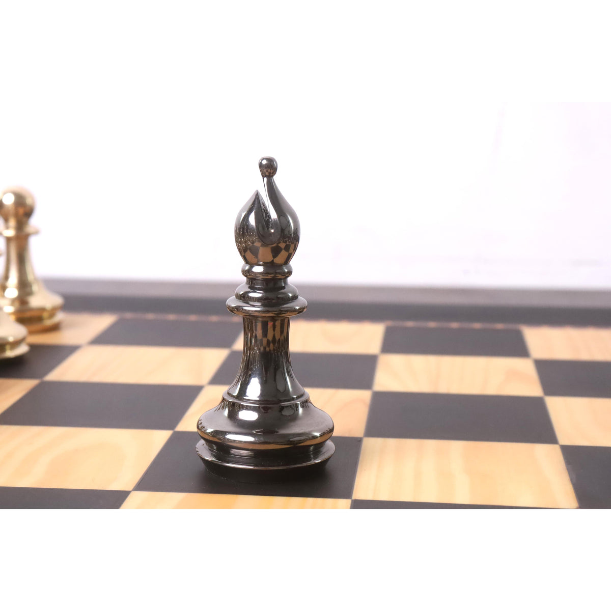 Sleek metallic grey brass bishop chess piece standing on a wooden chessboard square.