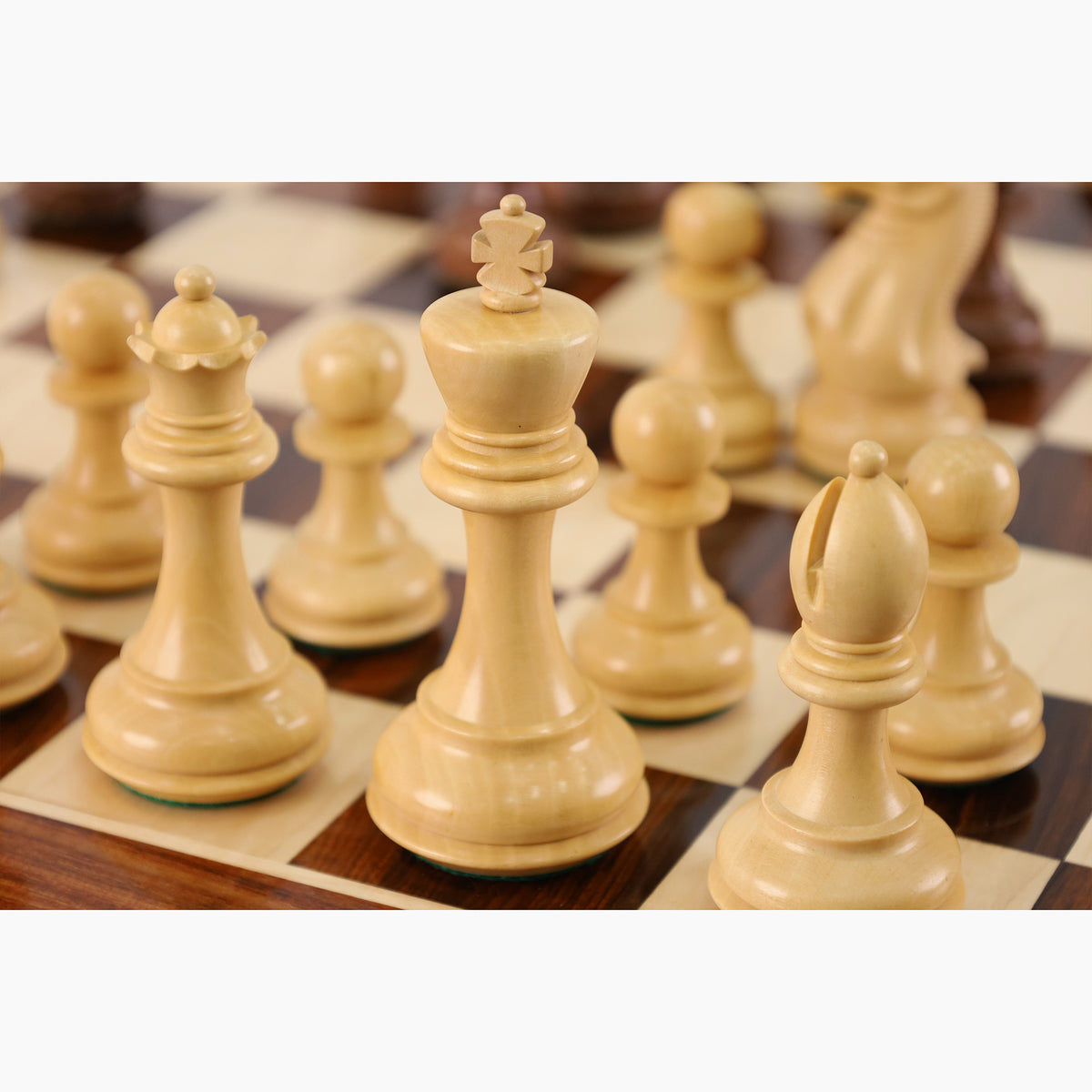 Elegant light boxwood king and queen pieces from a professional weighted Staunton chess set on a luxury board.