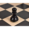 Close-up of an ebonised boxwood Staunton pawn chess piece on a wooden board.