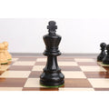 Black ebonised Staunton king chess piece centered on a wooden tournament chessboard.