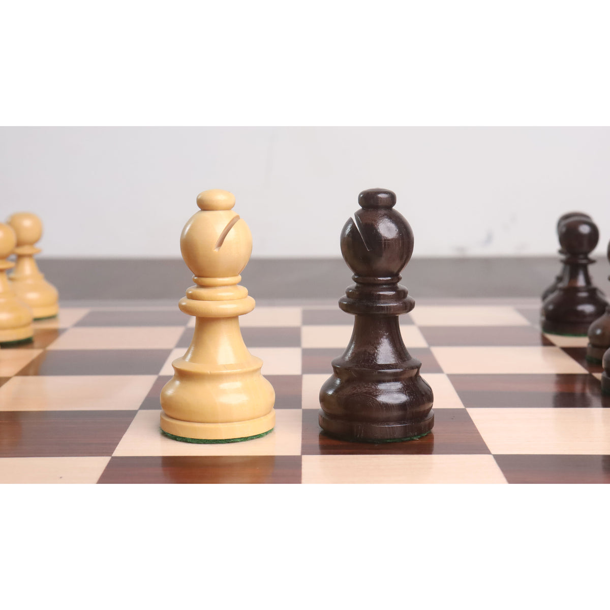 Premium boxwood and dark rosewood bishop chess pieces standing adjacent on a polished checkered wood board.