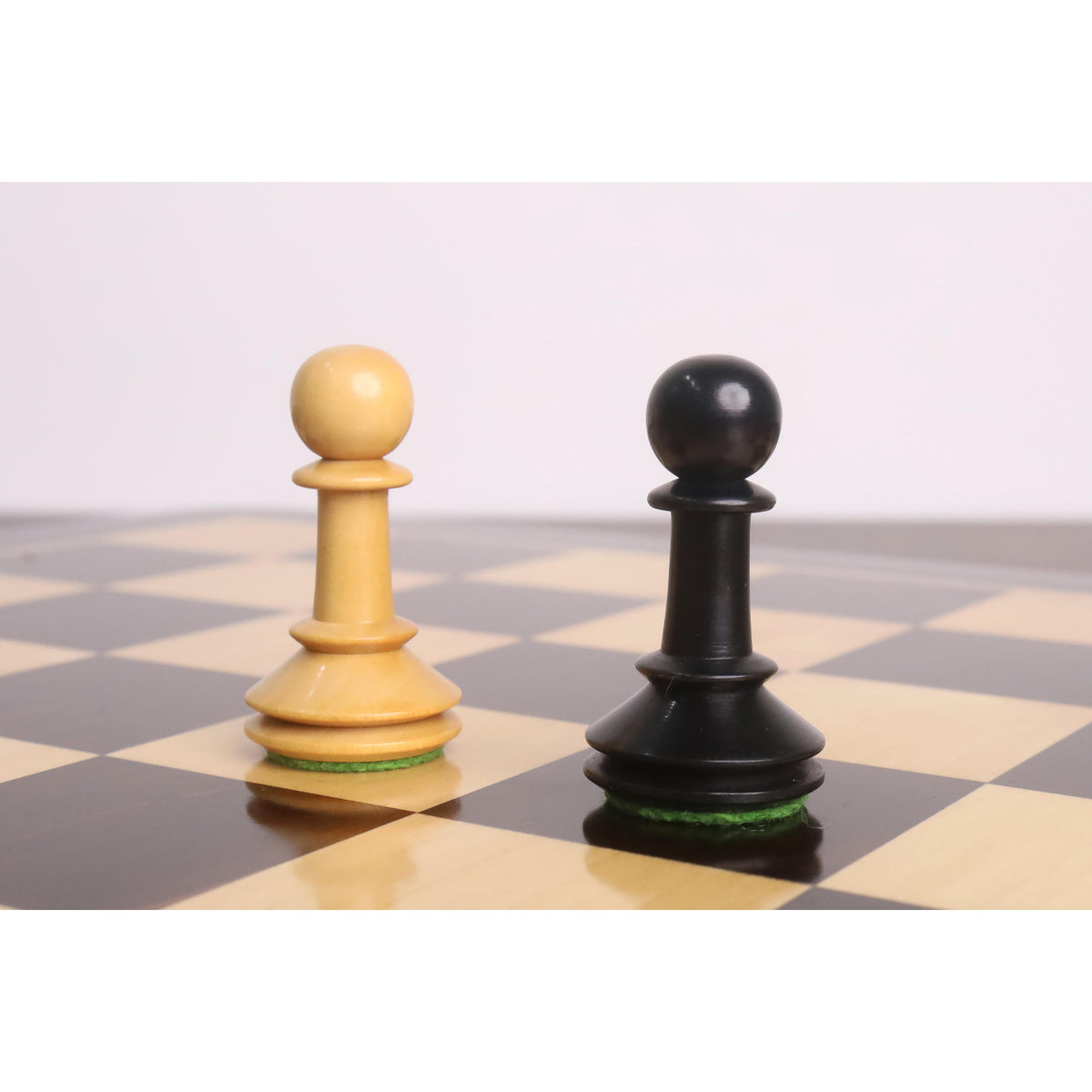 Boxwood and ebonised pawns from the 3.5-inch Monolith miniature chess set standing together on a chessboard.