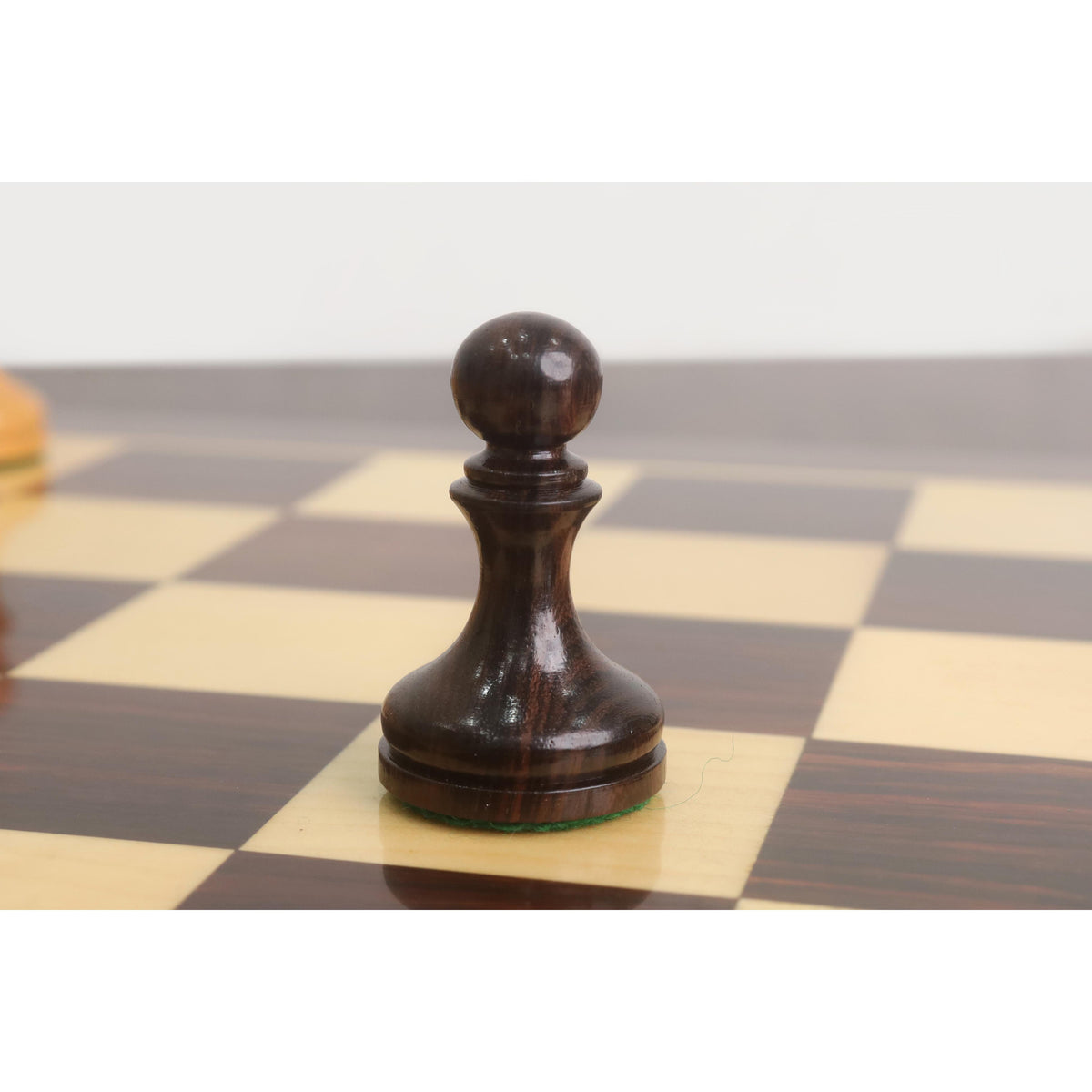 Close-up of the dark rosewood pawn from the 3.8" Candidates Series minimalist chess set on a wooden board.